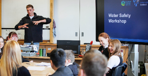 Duncan Scott Presents to the High School Pupils Duncan Scott stands at the front of a classroom presenting. Pupils sit smiling and laughing in the foreground.
