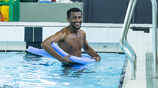 Never Too Late Learn to Swim Amanuel Akulu in a swimming pool taking adult swimming lessons as part of the Never Too Late Learn to Swim programme