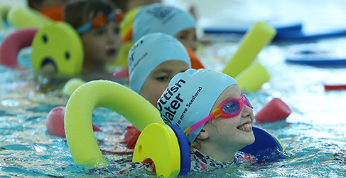 Learn to Swim Partnership 200K Milestone smiling kids using floats in pool