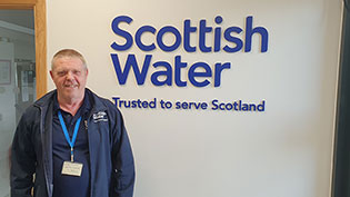 Man standing against a logoed wall