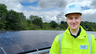 Man in hi viz jacket standing in front of Solar Panels