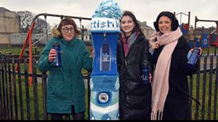 3 women standing with water bottles at a top up tap